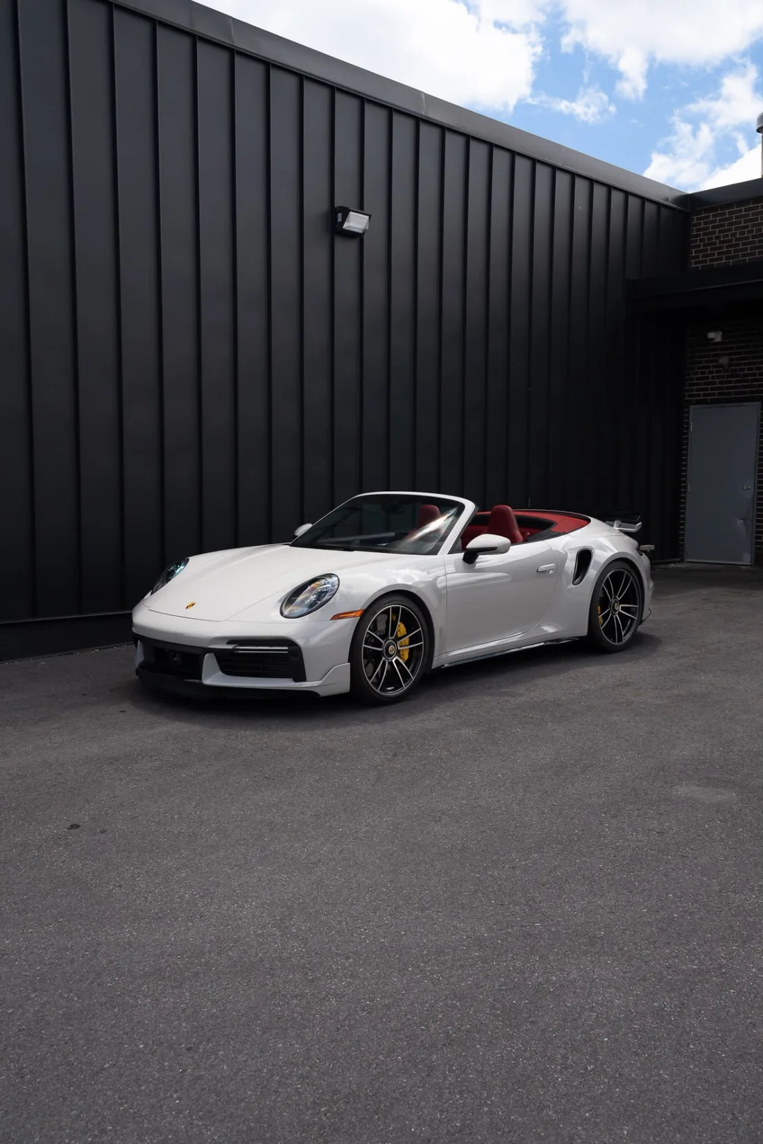 Porsche 911 Turbo S Cabriolet blanche devant un mur noir